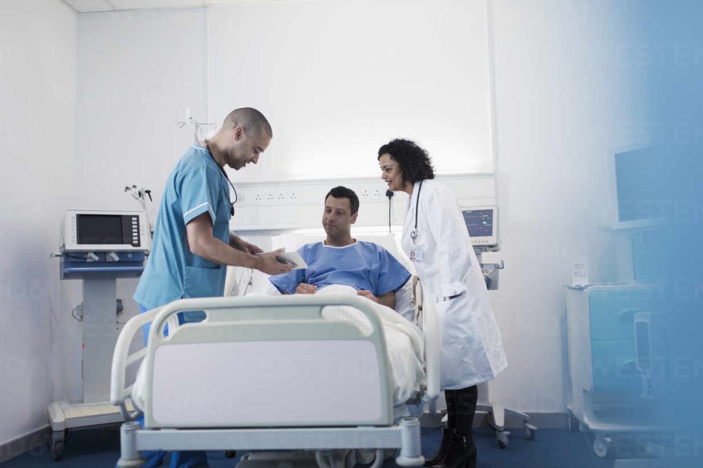 Healthcare professionals review AI data on a tablet in a hospital hallway, symbolizing the implementation of AI safety protocols in clinical settings.